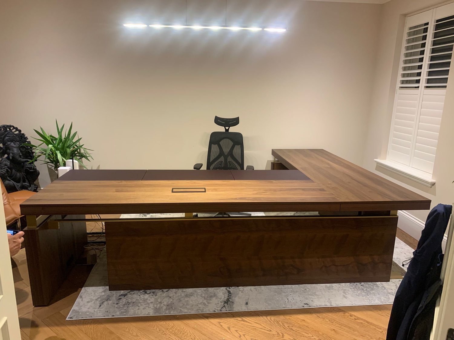 A bespoke walnut executive desk assembled in a home office, with plantation shutters fitted at the window